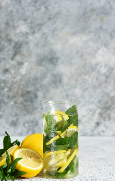 Lemonade with syrup and mint in a glass cup on a concrete background.