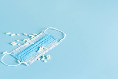 Mavi arka planda haplar ve tıbbi maske. Karantina.