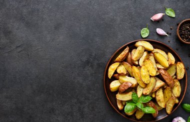 Siyah arka planda tuzlu ve sarımsaklı kızarmış patates dilimleri. Yukarıdan görüntüle.