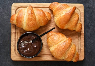 Tahta üzerinde kruvasan ve çikolata ezmesi. Yukarıdan görüntüle.