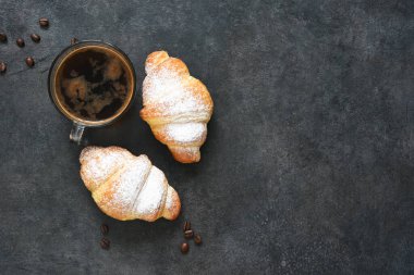 Siyah beton arka planda espresso ile kruvasan. Yukarıdan görünüm.