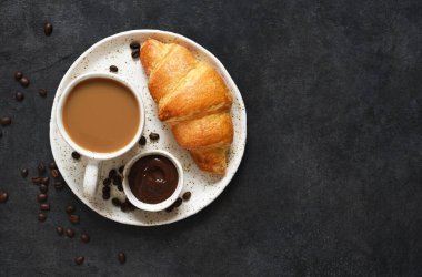 Siyah beton arka planda Maccafe olan kruvasanlar. Yukarıdan görünüm.