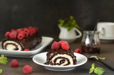 Krem peynirli ve ahududulu çikolata rulosu, koyu arkaplanda bir fincan kahve..