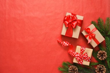 Kırmızı arka planda köknar ile güzel bir Noel kompozisyonu. Kırmızı kurdeleli hediye kutuları.