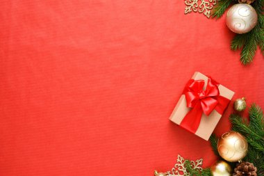 Kırmızı arka planda köknar ile güzel bir Noel kompozisyonu. Kırmızı kurdeleli hediye kutuları.