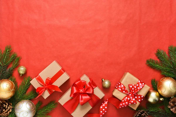 Beautiful Christmas composition on a red background with fir. Gift boxes with red ribbons.