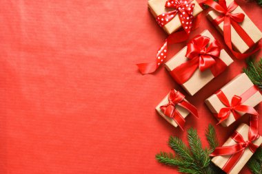 Kırmızı arka planda köknar ile güzel bir Noel kompozisyonu. Kırmızı kurdeleli hediye kutuları.