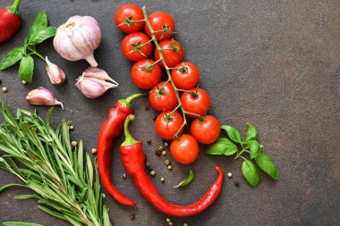 Baharatlar, acı biberler ve koyu beton arka planda domatesler. Yukarıdan görüntüle.
