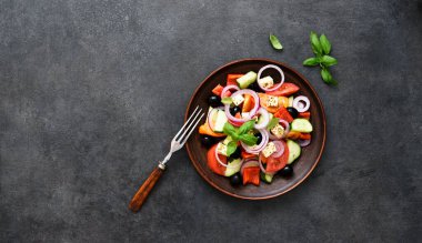 Siyah beton arka planda beyaz peynirli ve zeytinli Yunan salatası. Yukarıdan görüntüle.