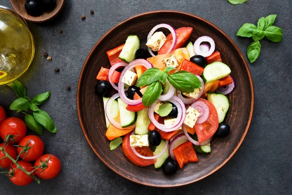 Siyah beton arka planda beyaz peynirli ve zeytinli Yunan salatası. Yukarıdan görüntüle.