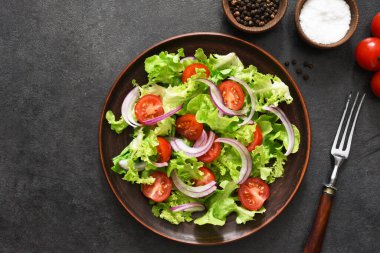 Domatesli sebze salatası, kırmızı soğan ve siyah arkaplanda sos..