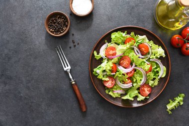 Domatesli sebze salatası, kırmızı soğan ve siyah arkaplanda sos..