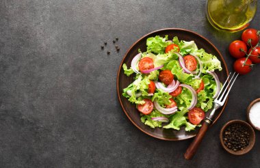 Domatesli sebze salatası, kırmızı soğan ve siyah arkaplanda sos..