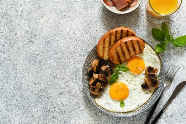 İngiliz kahvaltısı. Mantarlı sahanda yumurta ve kahvaltıda bir bardak portakal suyu ile jambon. Günaydın..