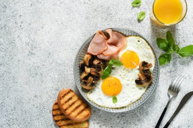 İngiliz kahvaltısı. Mantarlı sahanda yumurta ve kahvaltıda bir bardak portakal suyu ile jambon. Günaydın..