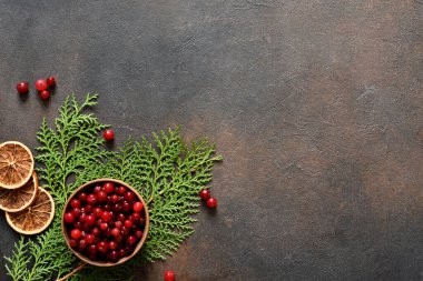 Beton bir arka planda kozalaklı ağaç ve kızılcıklı Noel süslemesi.