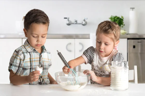little boy and girl cook cake in kitchen