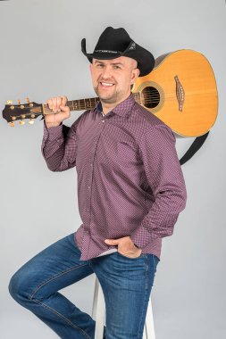 Siyah kovboy şapkalı adamın portresi. O bir gitar bir omuz üzerinde ayılar.