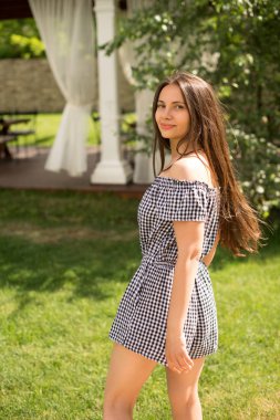 Damalı siyah-beyaz tulum giyen genç kadın esmer park üzerinde gider, görünür mesafedir Restoran