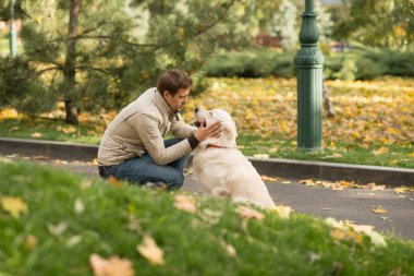    Biege'e ceket ve kot giyen genç adam ile onun büyük köpek Labrador bir sonbahar park dostudur. Birbirlerine benziyorlar, karşılıklı anlayış var..