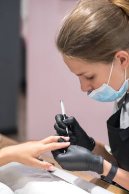 Bir güzellik salonu manikür süreci yakın çekim. Siyah eldiven manikür master çivi işleme özel ekipman kadınla yapar.