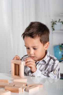 Çocuk kapalı bir masada oturur ve heyecanla ahşap Oluşturucu içinde çalış.