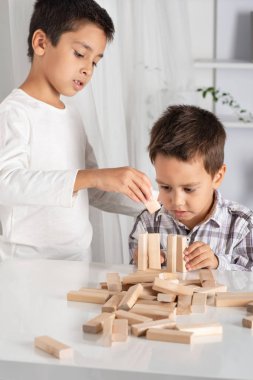 Çocuk kapalı bir masada oturur ve heyecanla ahşap Oluşturucu içinde çalış. Büyük oğlan ona yardımcı olur.