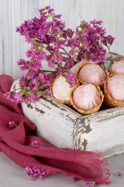 Beş gözleme koniler ile tatlı çilek siyah frenk üzümü yaban mersini taze çilek ile dekore edilmiş antik bir beyaz tahta kutuya yalan. Yakın bir kaç dal pembe çiçek ve pembe keten peçete yalan.