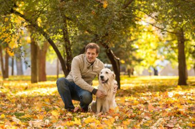 Duygusal kot pantolon ve mavi bir ceket giymiş küçük bir çocuk büyük bir beyaz Labrador köpek kucaklar. Sonbahar parkta yürüyorlar. Genç bir adam köpeğiyle Labrador bir sonbahar park dostudur. Birbirlerine benziyorlar, karşılıklı lanet var.