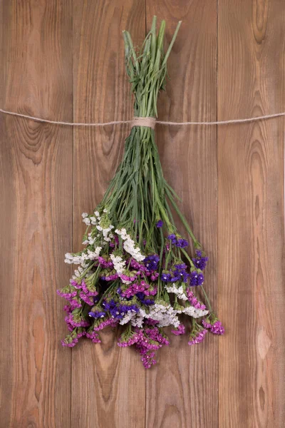  Kuru çiçekler limonium çok renkli, jüt halat ile bağlı asmak bir kahverengi ahşap duvar veya çit