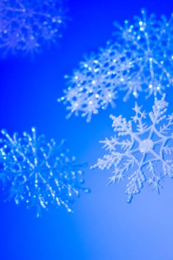 Mavi bir arka plan üzerinde dekoratif kar taneleri. Neşeli Noel ve mutlu yeni yıl