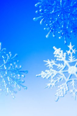 Mavi bir arka plan üzerinde dekoratif kar taneleri. Neşeli Noel ve mutlu yeni yıl