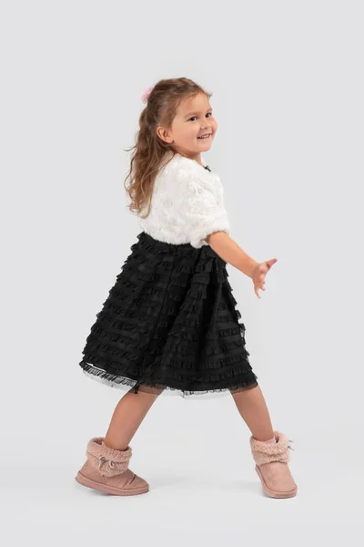 一个面带微笑的小女孩穿着美丽的黑色优雅礼服的全长肖像 她站在演播室的白色背景上 — 图库照片