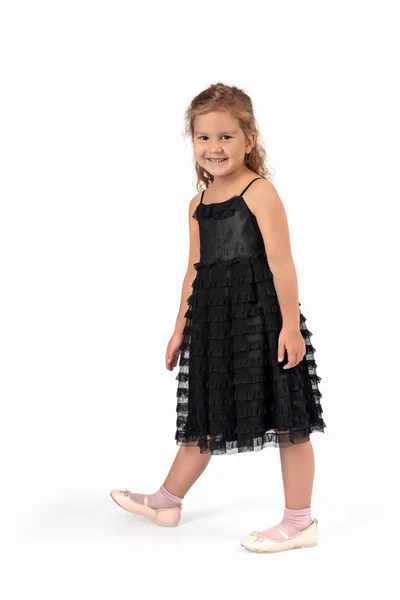 一个面带微笑的小女孩穿着美丽的黑色优雅礼服的全长肖像 她站在演播室的白色背景上 — 图库照片