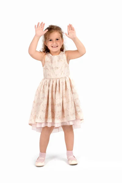 一个面带微笑的小女孩穿着美丽的米色优雅礼服的全长肖像 她站在演播室的白色背景上 举起双手 露出手掌 — 图库照片