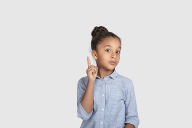 Duygusal portre Studio gri arka plan üzerinde mavi gömlek giymiş melez kıvırcık kız kapatın. O işaret parmağı kadar dikkat gösterir!