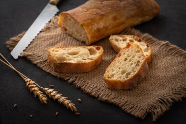  dilimlenmiş parçaları ve buğday yalan bir tabloda Jüt peçeteye kulakları ile geleneksel ciabatta ekmeği. Sonraki bir bıçak olduğunu