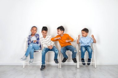 Duygusal stüdyo çekim, çocuk, kız ve üç erkek bekleyen iskemlede oturuyor. Çocuklar oynayabilir ve kavga, kız memnun bir yüzü var, beklemekten yorgun