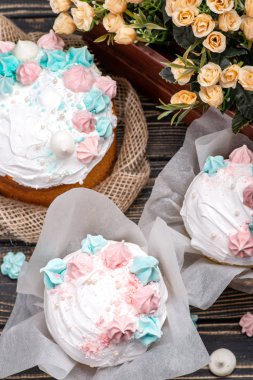 Ağaç lezzetli süsleyin Paskalya kek yalan Beyaz ahşap bir masa üzerinde bir yuvarlak Beyaz ahşap plaka üzerinde. Bir tepsi pasta ve çiçekler ile masaya standı. 