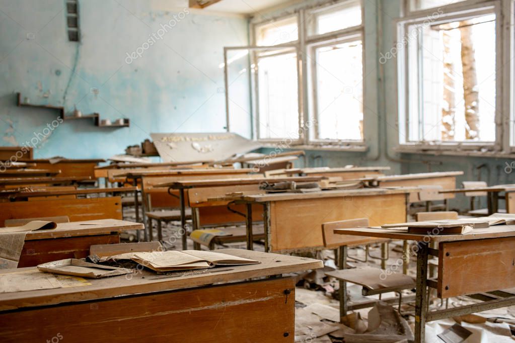  The thrown and destroyed soviet school in Pripyat after the Chernobyl accident in Ukraine in 1986. School desks and scattered textbooks in one of the school classes.