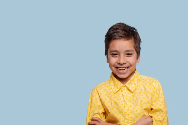 Studioaufnahme eines lachenden Jungen mit gelbem T-Shirt auf blauem Hintergrund — Stockfoto