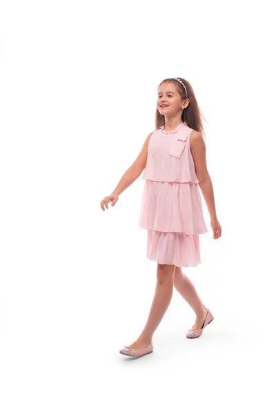 Studio plan d'une petite fille souriante portant une robe de soleil rose sur un — Photo