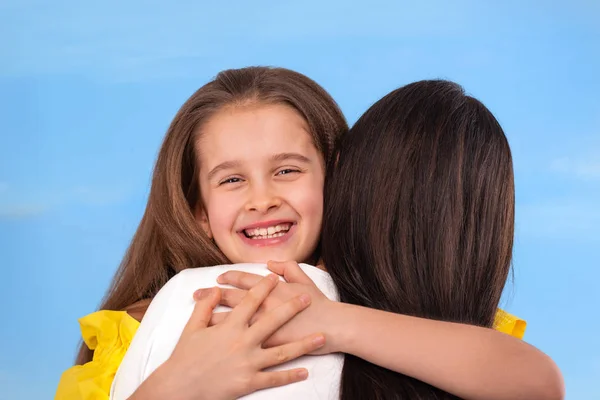 Studioaufnahme der Umarmung von Mutter und Tochter vor blauem Himmel. — Stockfoto