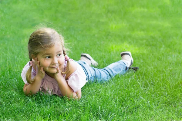 Meisje met vlechtjes liggend op het groene gras — Stockfoto