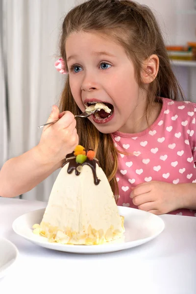 Estúdio tiro de menina pequena sentada a uma mesa e comer Páscoa — Fotografia de Stock