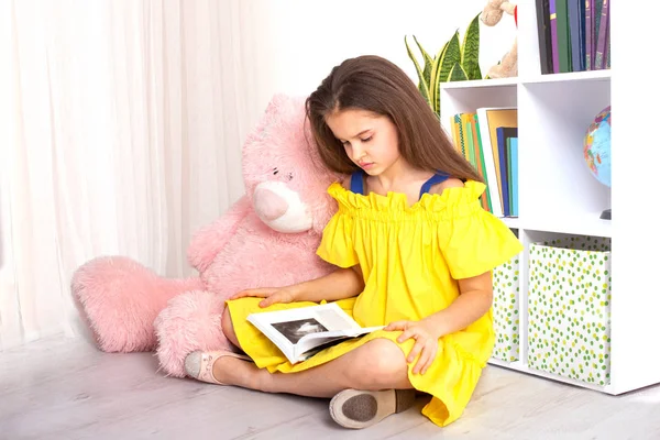 Studio laukaus pikkutyttö yllään keltainen sundress istuu — kuvapankkivalokuva