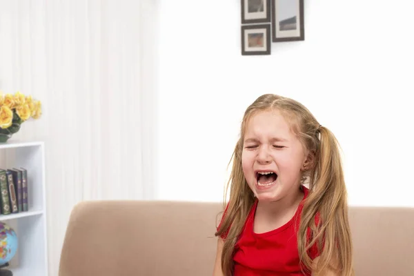Маленька дівчинка сидить на дивані і плаче, сльози течуть вниз — стокове фото