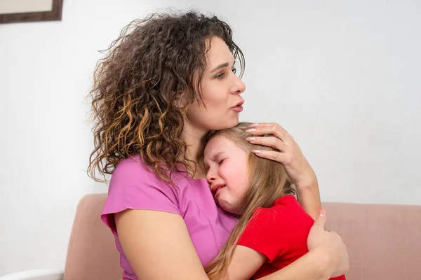 Een jonge moeder kalmeert haar dochtertje. Het meisje huilt een — Stockfoto