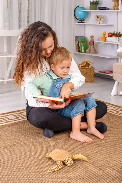 Молода мати або няня з маленьким хлопчиком сидить на підлозі — стокове фото