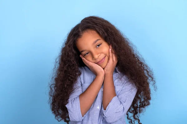 Waist up emotional portrait of mulatta frizzy girl wearing blue